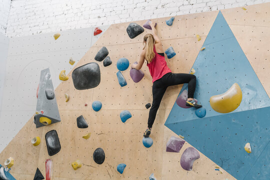 Woman bouldering in climbing gym