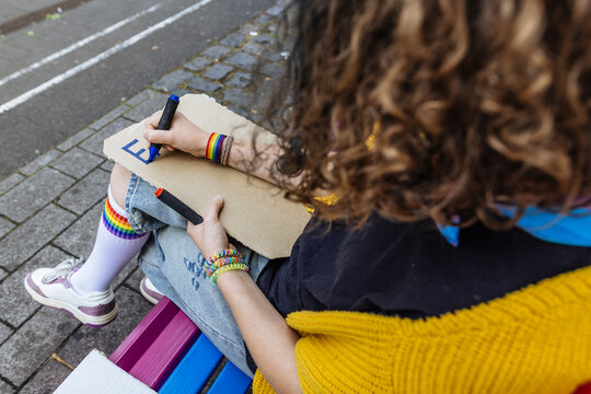 Activist writing on cardboard sign for pride parade outdoors