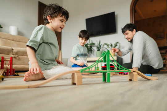 Father and children playing with toy train at home