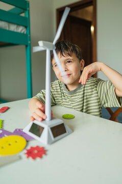 Student observing a model windmill and solar panel indoors