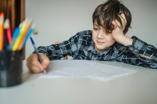 Fatigued schoolboy studying lessons at home