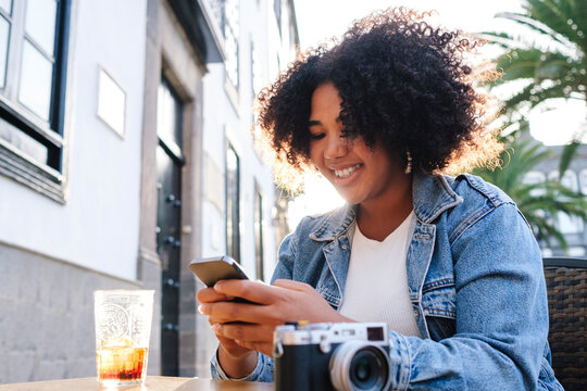 Happy woman using smart phone sitting in cafe