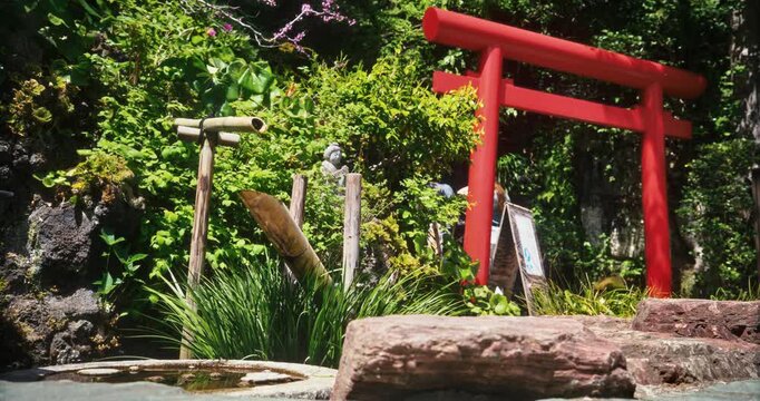 Red Torii Gate with Bamboo Fountain and Stone Basin in Japanese Garden - Low Shot