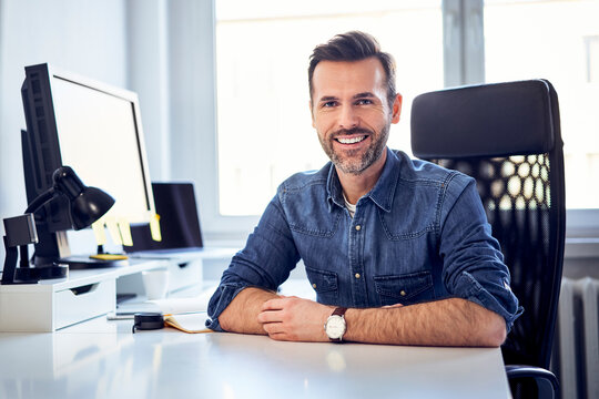 Portrait of smiling man sitting at desk in office
