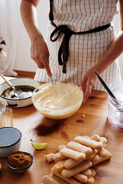 Woman stirring Mascarpone cream for preparing Tiramisu, partial view