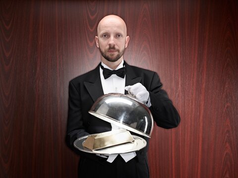 Butler presenting a gold bar on a silver tray