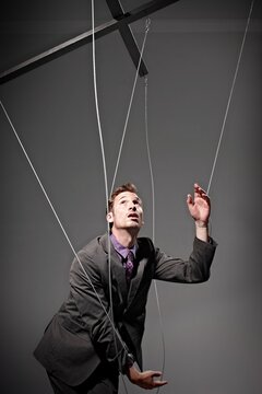 Businessman manipulated like a marionette puppet on strings