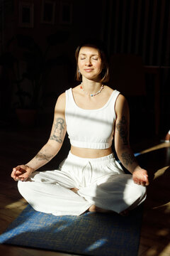Peaceful yoga teacher meditating indoors in sunlight