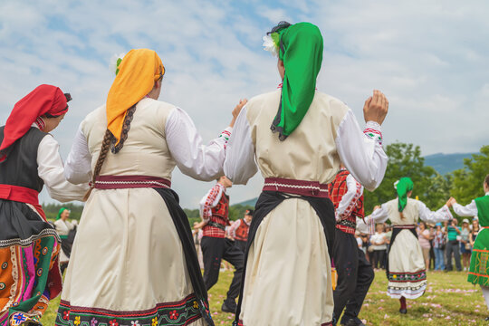 Women in Bulgaria costumes perform hora dance during folk festival with dancers holding hands outdoors. Hora dance, Bulgarian culture concept, cultural expression, traditional dance celebration