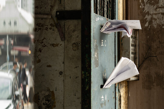 Weathered communal letterboxes with overflowing mail on a residential building entrance in Mong Kok, Kowloon, Hong Kong, labelled with Chinese-language flat identifiers (translations: 5C, 6A, 6B)