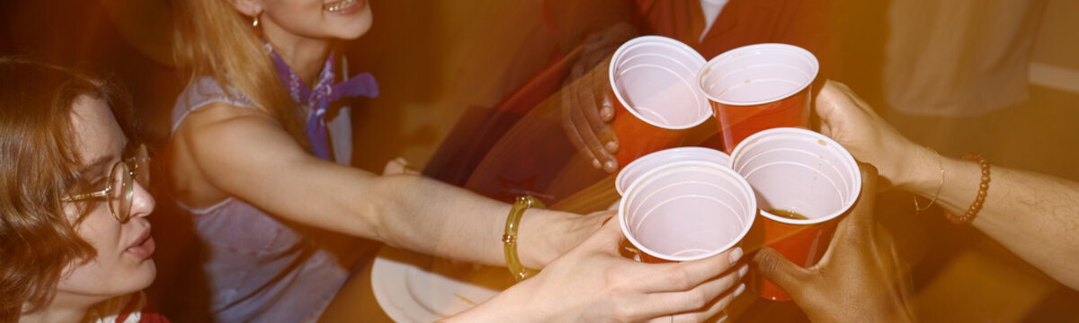 Website header shot of young adult friends celebrating Independence Day at home, raising plastic cups in toast and marking holiday gathering, for party promotion, seasonal marketing, social campaigns