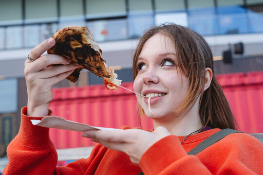 Youth enjoying a slice of cheese pizza outdoors
