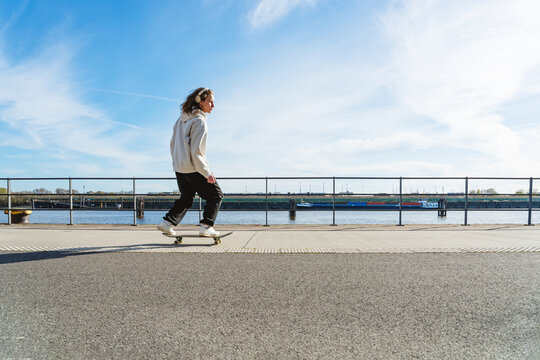 Skateboarder listening to music riding along the promenade
