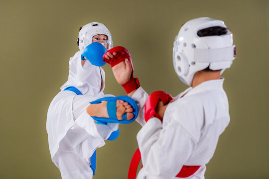 Karate athlete executes a front kick targeting the opponent's midsection while simultaneously throwing a punch, demonstrating combined upper and lower body attack coordination  