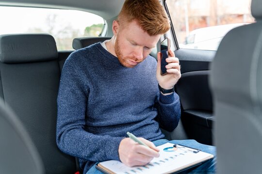 Businessman working in backseat with phone and financial chart