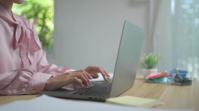 Close up of female hands typing on a modern laptop computer. A businesswoman working from home, responding to emails and managing projects
