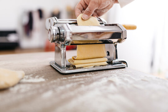 Chef rolling dough with pasta machine