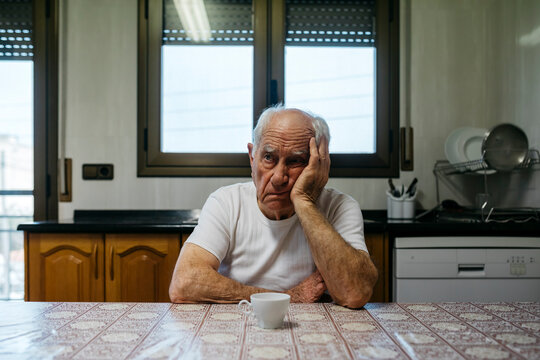 Sad man sitting at table in kitchen