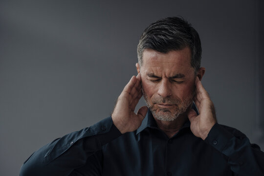 Portrait of mature businessman having earaches