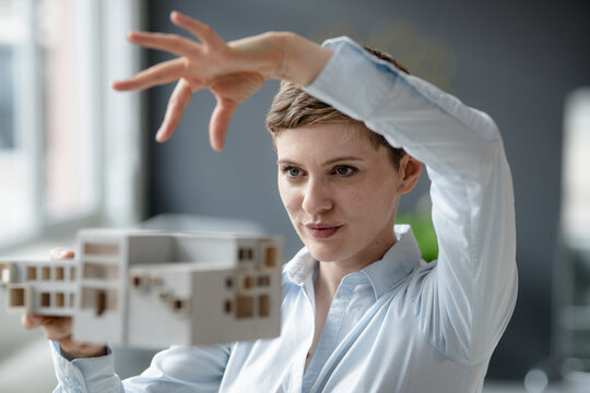 Confident businesswoman holding architectural model in office