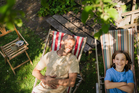 Father and son relaxing on deck chairs in sunny garden