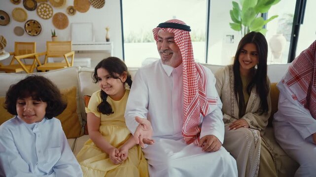 Multi-generation arab family wearing traditional saudi clothing smiling together in modern home