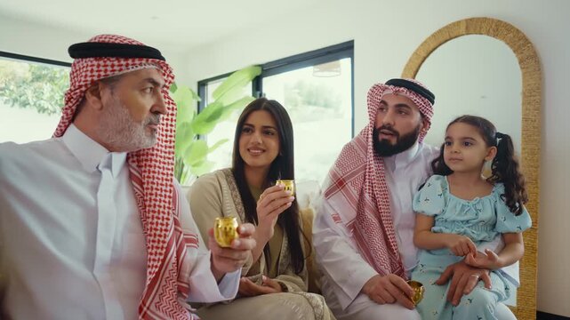 Multi-generation arab family wearing traditional saudi clothing smiling together in modern home