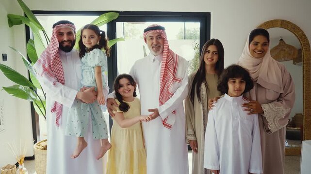 Arab multi-generational family wearing traditional saudi clothing smiling together in modern home