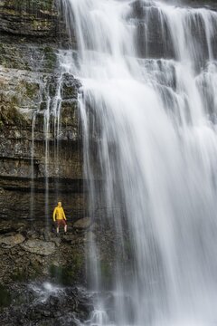 Adventure, Little hiker under large Cascata di Mezzo waterfall, long exposure, Vallesinella, Brenta, Trentino, Italy