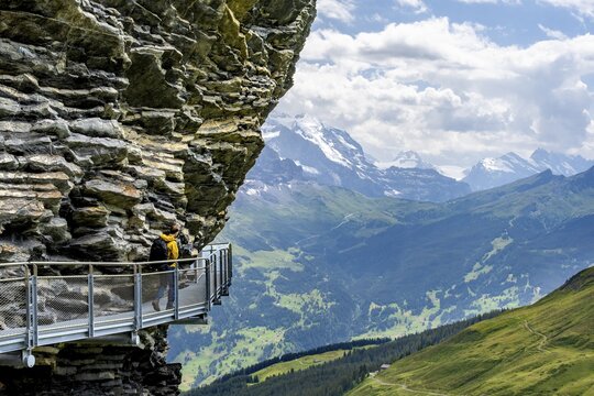 Young man on First Cliff Walk, metal trail on a rocky outcrop, Grindelwald First, in front of impressive mountain scenery, Bernese Alps, Bernese Oberland, Switzerland