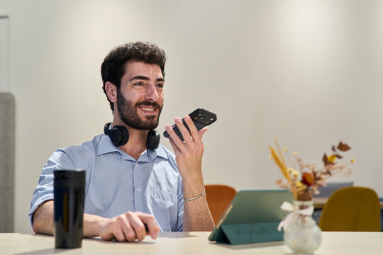 Entrepreneur sending voice message on smartphone in office
