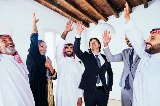 Diverse business team raising hand to celebrate success in office
