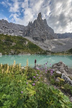 Young woman, hiker at the turquoise-green Sorapis lake, Lago di Sorapis, mountain peak Dito di Dio, Dolomites, Belluno, Italy
