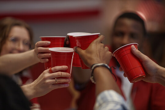 Diverse young adults raising cups and celebrating Independence Day at home, expressing friendship and holiday gathering. Ideal for seasonal marketing, party promotion, social campaigns