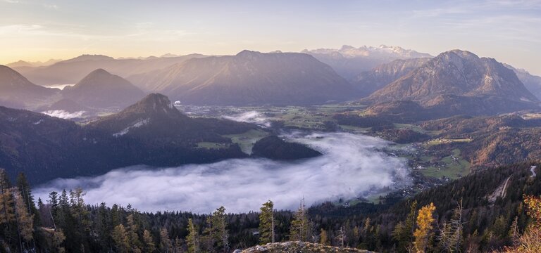 Panoramic photo: view from Mount Loser to Lake Altaussee, Altaussee, Bad Aussee, Tressenstein, Zinken, Sarstein, Dachstein mountains. Wafts of mist over the lake. In the morning at sunrise. Blue sky. Autumn, yellow larches. Altaussee, Bad Aussee, Ausseer Land, Totes Gebirge, Styria, Upper Austria, Austria