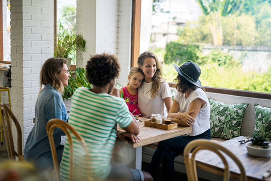 Happy friends with child socializing in cozy cafe