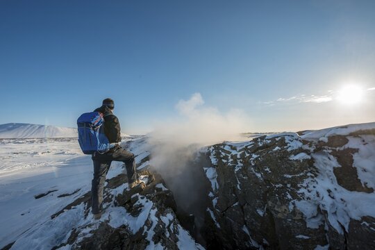 Mountain hiker stands at Continental Rift between North American and Eurasian Plate, Mid-Atlantic Ridge, Rift Valley, Silfra Rift, Krafla, North Iceland, Iceland