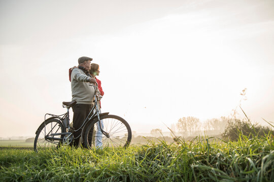 Senior man and daughter in rural landscape with bicycle