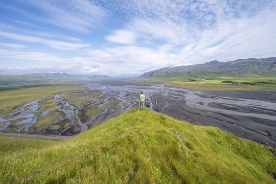 Hiker, young man on a hill, view over alluvial land, meandering river, D&iacute;monarhellir, Su&eth;urland, Iceland