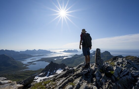 View of mountains and fjord landscape, mountaineer at the summit of Rundfjellet, Sun Star, Austenesfjord fjord, Svolvaer, Nordland, Norway
