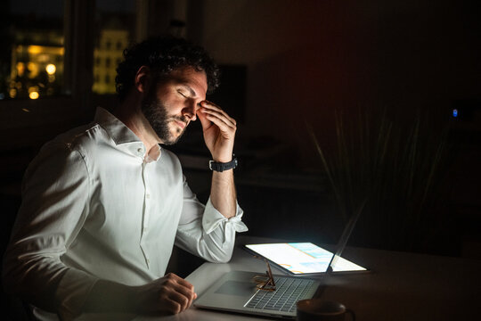 Tired business professional working late at night in dark office