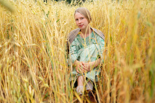 Model resting in a summer wheat field in a floral dress