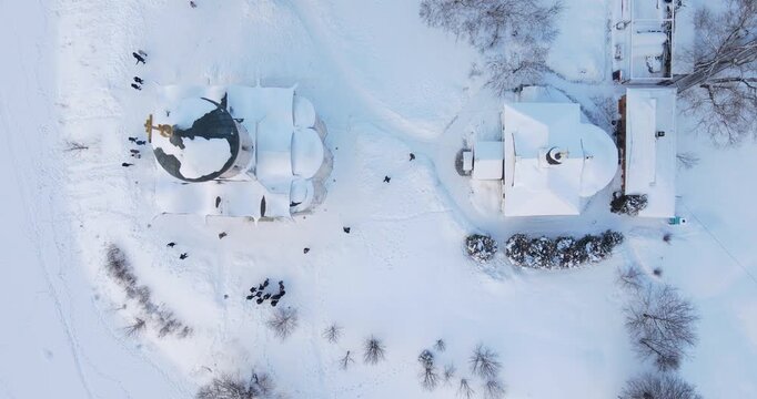 Cinematic aerial shot flying directly over the historic white stone Church of the Intercession on the Nerl in a snowy winter landscape near Bogolyubovo, Russia