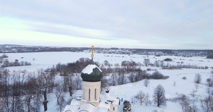 Cinematic aerial drone pull back shot revealing the historic Church of the Intercession on the Nerl in a snowy winter landscape