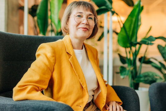 Smiling businesswoman in yellow blazer sitting in coworking space