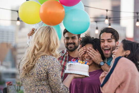 Friends celebrating birthday party on rooftop with birthday cake