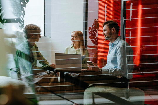 Business colleagues having meeting with laptop in modern glass office