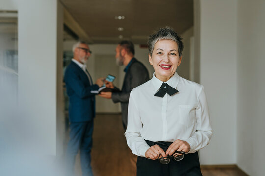 Businesswoman smiling in office with colleagues in background