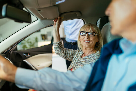 Senior couple trying out car in car dealership