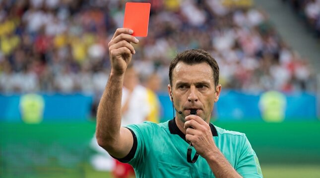 Close up football referee holding red card in stadium during match, serious decision on field